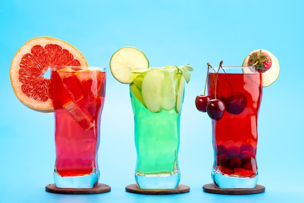 Photo gratuite une vue de face des cocktails de fruits frais avec des tranches de fruits frais refroidissement par glace sur bleu, boire du jus de fruits cocktail couleur de fruits
