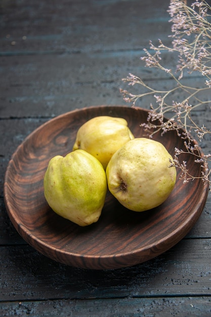 Vue de face coings mûrs frais fruits aigres à l'intérieur de la plaque sur un bureau rustique bleu foncé plante fruit mûr arbre frais