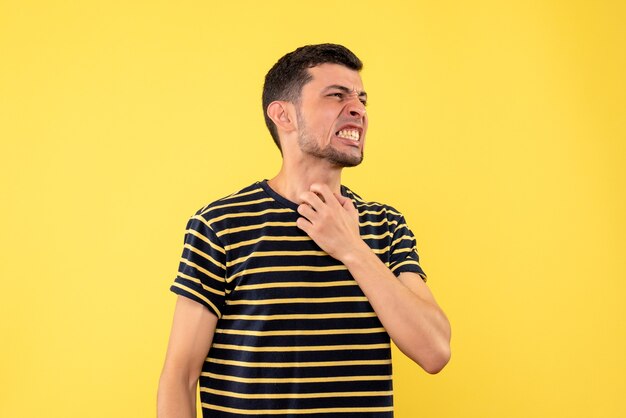 Vue de face en colère jeune homme en t-shirt rayé noir et blanc fond isolé jaune