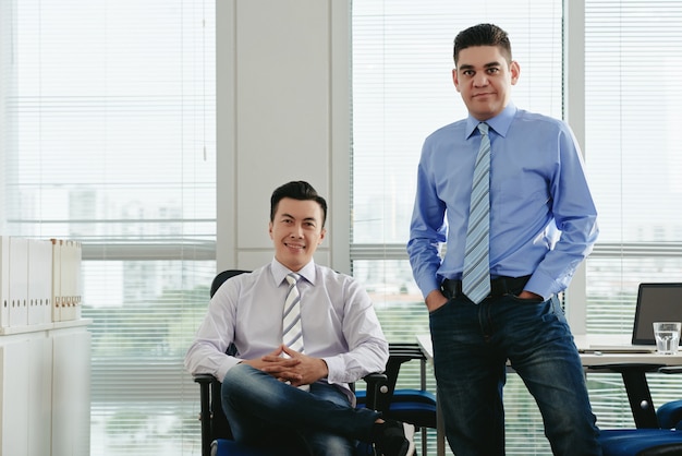 Vue de face de collègues masculins regardant la caméra dans leur bureau