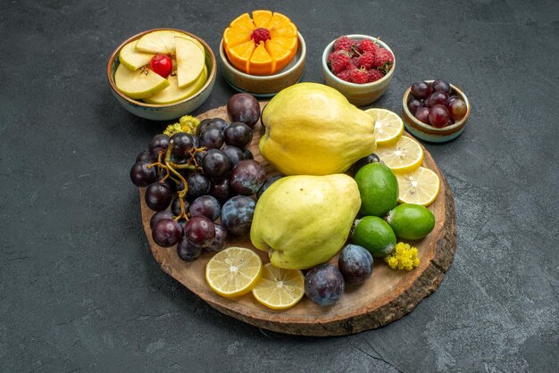 Vue de face composition de différents fruits frais et mûrs sur fond gris foncé fruits mûrs mûrs santé couleur des plantes