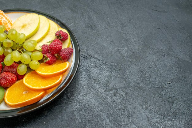 Vue de face composition de fruits délicieux fruits frais tranchés et moelleux sur fond sombre régime de santé mûr frais et moelleux