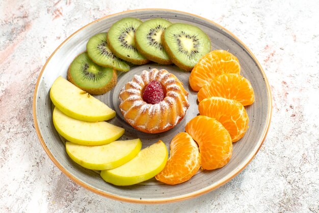 Vue de face composition de fruits différents fruits frais et tranchés avec gâteau sur fond blanc santé des fruits mûrs moelleux