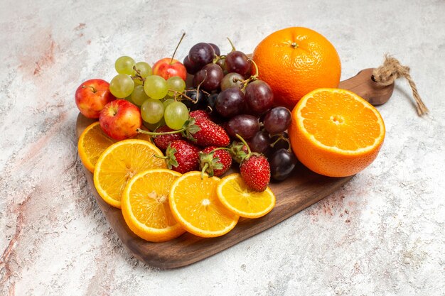 Vue de face de la composition de fruits frais oranges raisins et fraises sur espace blanc