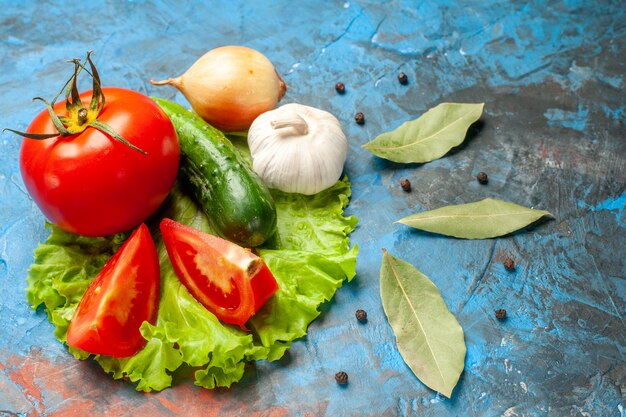 Vue de face concombre de légumes frais avec salade verte de tomate et ail sur fond bleu repas salade santé aliments mûrs régime couleur