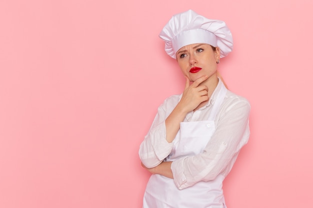 Vue de face confiseur en vêtements blancs posant avec expression de pensée sur le travail de travail de pâtisserie sucrée confiserie bureau rose clair