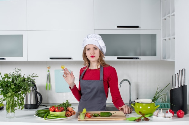 Vue de face confus chef féminin en tablier debout derrière la table