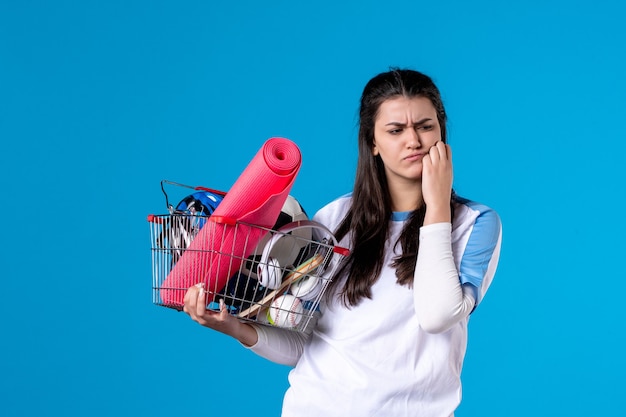 Vue de face confus jeune femme avec panier après le sport shopping