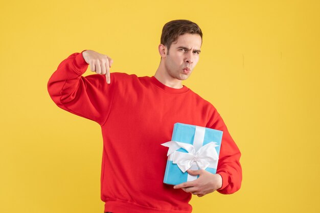 Vue de face confus jeune homme avec pull rouge debout sur jaune