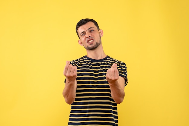 Vue de face confus jeune homme en t-shirt rayé noir et blanc fond isolé jaune