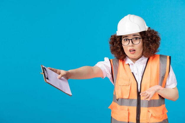 Vue de face constructeur féminin nerveux en uniforme sur bleu