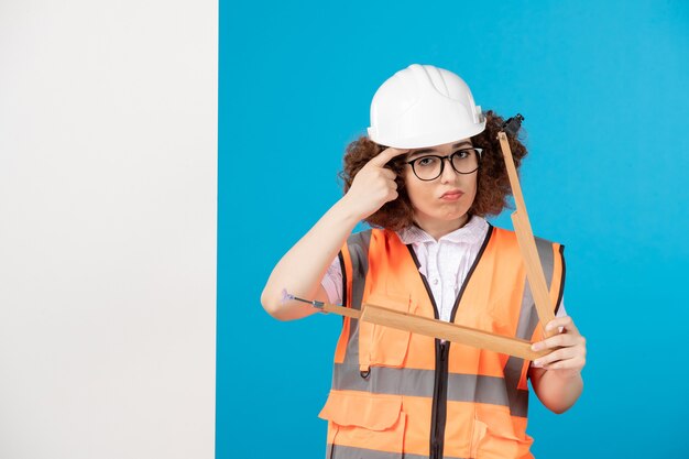 Vue de face constructeur féminin en uniforme sur le bleu