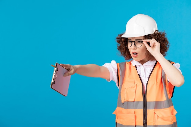 Photo gratuite vue de face constructeur féminin en uniforme avec note sur bleu