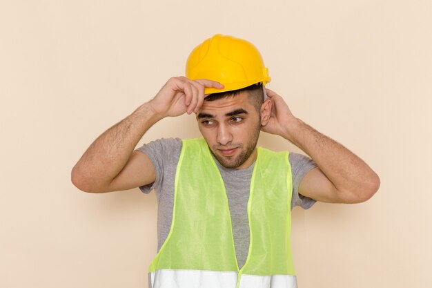Vue de face constructeur masculin en casque jaune posant sur le fond clair