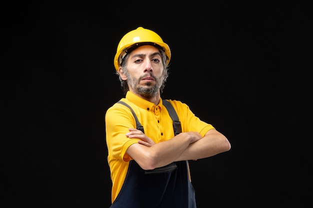 Vue de face constructeur masculin en uniforme sur mur noir