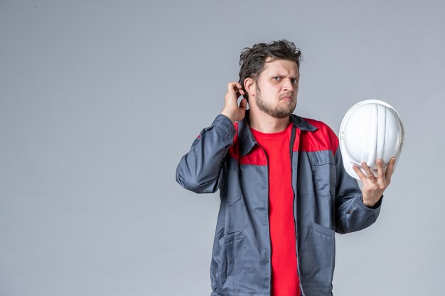 Vue de face constructeur masculin en uniforme tenant un casque blanc sur fond clair