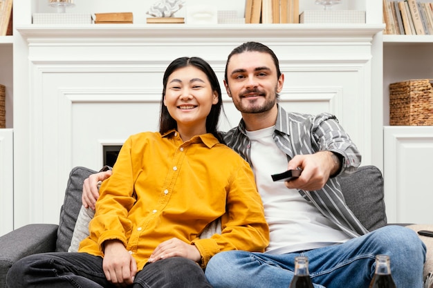 Vue de face couple assis sur le canapé à regarder la télévision