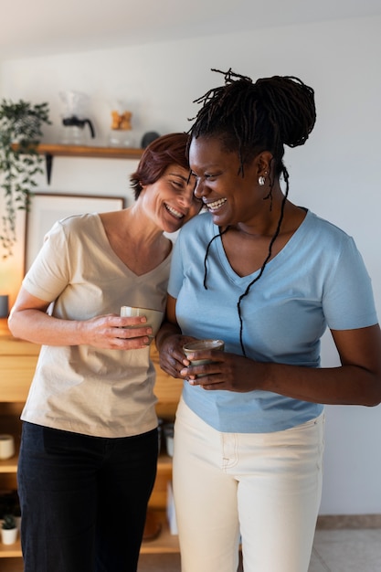 Photo gratuite vue de face couple de lesbiennes avec des tasses à café