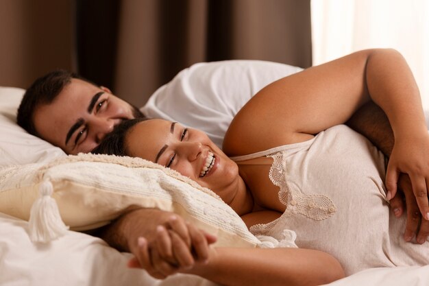 Vue de face couple souriant au lit