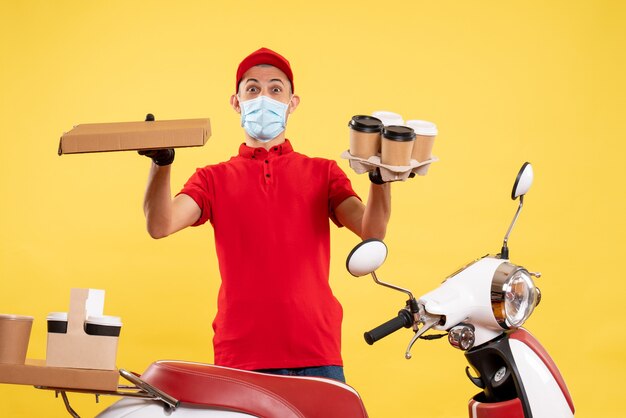 Vue de face de courrier masculin en uniforme avec du café et de la nourriture fort sur le travail de service de pandémie jaune travail uniforme covid couleurs du virus de l'emploi