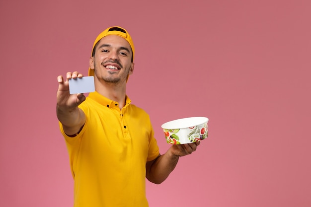 Vue de face de courrier masculin en uniforme jaune tenant le bol de livraison avec carte sur le fond rose.