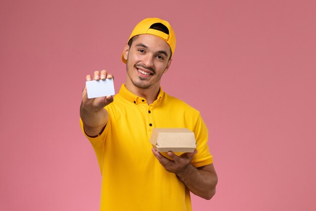 Vue de face de courrier masculin en uniforme jaune tenant la carte et petit paquet de nourriture sur fond rose.