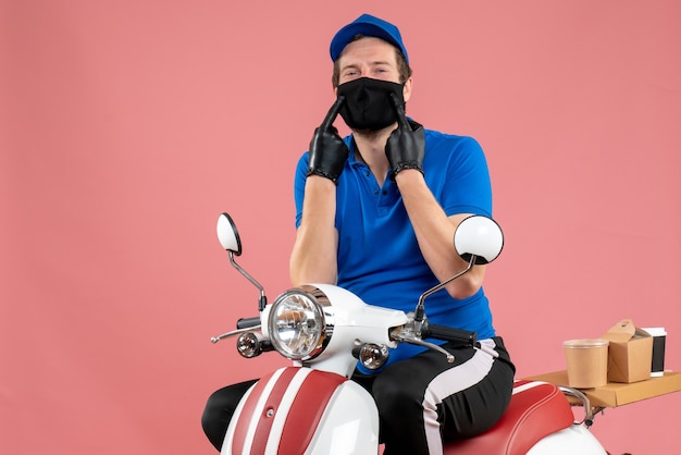Vue de face coursier masculin en uniforme bleu et masque sur le vélo rose service fast-food covid- travail virus de l'emploi