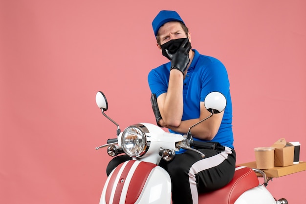 Vue de face coursier masculin en uniforme bleu et masque sur le virus de la livraison rose service de restauration rapide restauration vélo travail covid- job