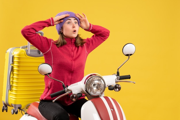 Photo gratuite vue de face déconcerté jeune fille sur un cyclomoteur en regardant quelque chose avec un grand intérêt