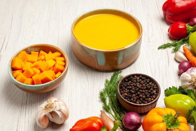 Vue de face délicieuse crème de soupe à la citrouille texturée avec des légumes sur un bureau blanc repas de sauce à soupe mûre