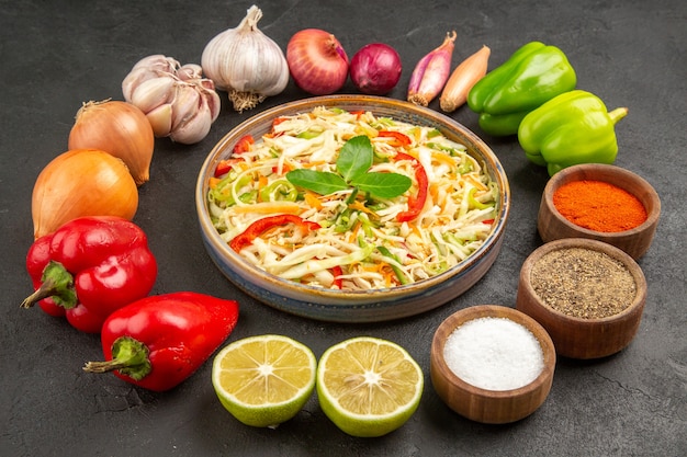 Vue de face délicieuse salade de légumes avec assaisonnements et légumes frais sur la table grise