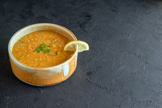 Vue de face délicieuse soupe aux lentilles avec tranche de citron à l'intérieur de la petite assiette sur une surface sombre