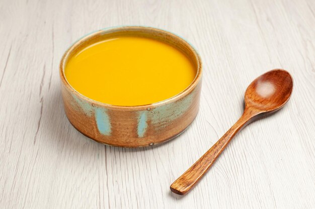 Vue de face délicieuse soupe à la crème soupe de couleur jaune sur un bureau blanc soupe sauce repas crème dîner plat