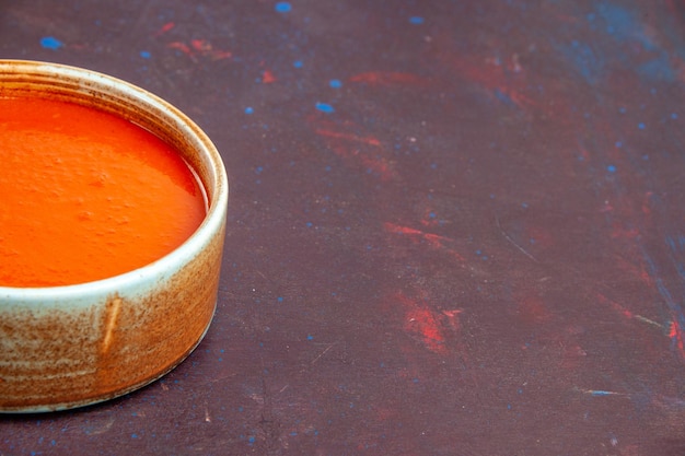 Vue de face délicieuse soupe de tomates cuite à partir de tomates fraîches sur un espace sombre