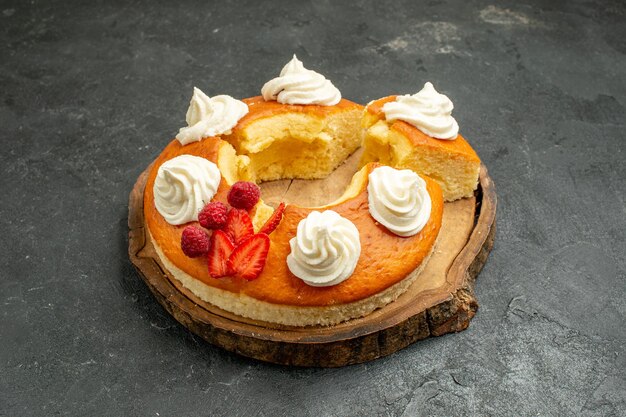 Vue de face délicieuse tarte ronde tranchée avec de la crème blanche sur un espace gris