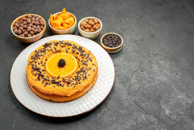 Vue de face délicieuse tarte sucrée avec des tranches d'orange sur fond gris foncé tarte biscuit dessert gâteau sucré thé