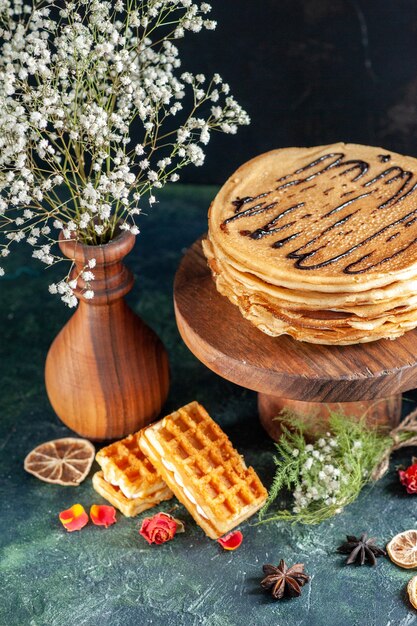 Vue de face de délicieuses crêpes avec des biscuits sur une surface bleu foncé