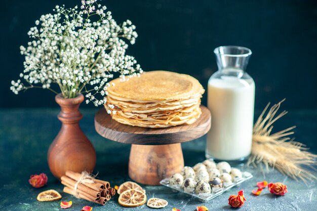 Vue de face de délicieuses crêpes sur un bureau en bois et une tarte au gâteau de petit-déjeuner sombre au miel, au thé du matin, au lait de dessert