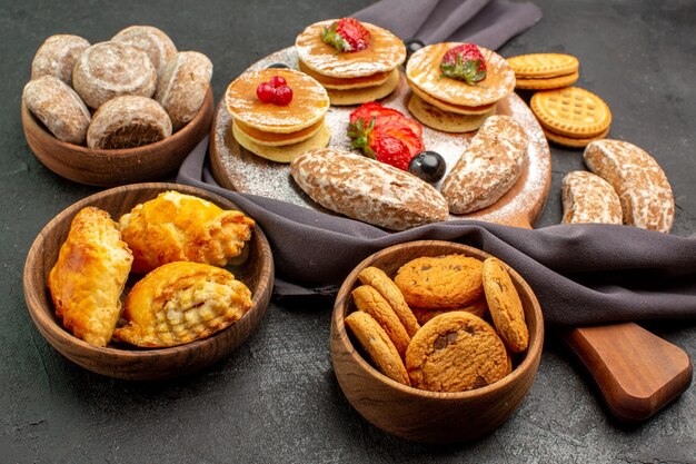 Vue de face de délicieuses crêpes avec des fruits et des gâteaux sucrés sur une surface sombre dessert gâteau sucré