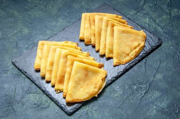 Vue de face de délicieuses crêpes sur une pâtisserie de couleur bleu foncé cuire au four à tarte à la pâte à gâteau au petit déjeuner viande