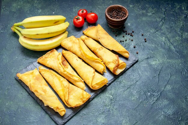 Vue De Face De Délicieuses Crêpes Roulées Avec Des Bananes Sur Une Surface Sombre