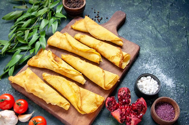 Vue de face de délicieuses crêpes roulées sur un repas sombre tarte à la viande pâtisserie hotcake bonbons couleur pâte gâteau