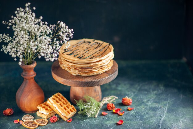 Vue de face de délicieuses crêpes sur une surface bleu foncé