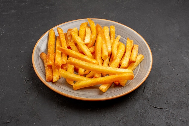 Vue de face de délicieuses frites à l'intérieur de la plaque sur un espace sombre