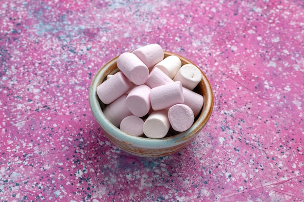 Photo gratuite vue de face de délicieuses guimauves sucrées peu formées à l'intérieur d'un pot rond sur un bureau rose.