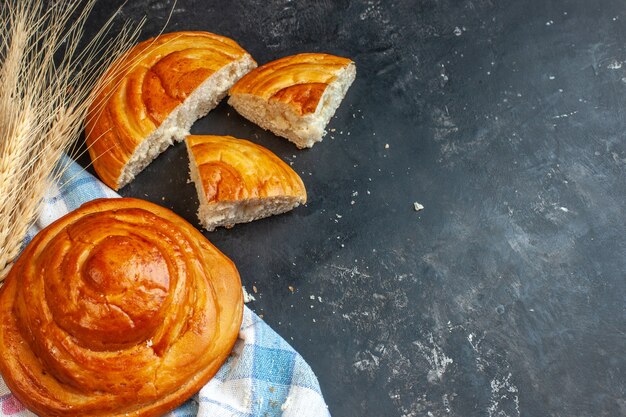 Vue de face de délicieuses pâtisseries entières et coupées sur une serviette à rayures bleues et une pointe sur le côté gauche sur bleu