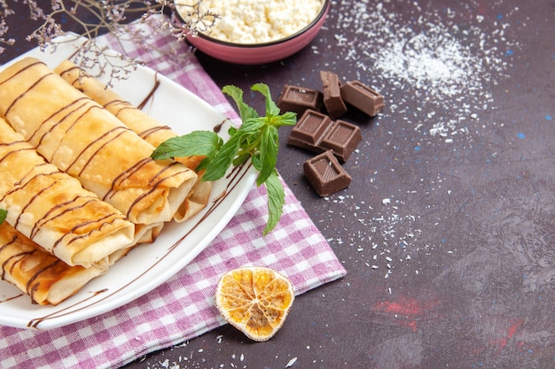 Vue De Face De Délicieuses Pâtisseries Sucrées Avec Des Barres De Chocolat Sur Un Espace Sombre