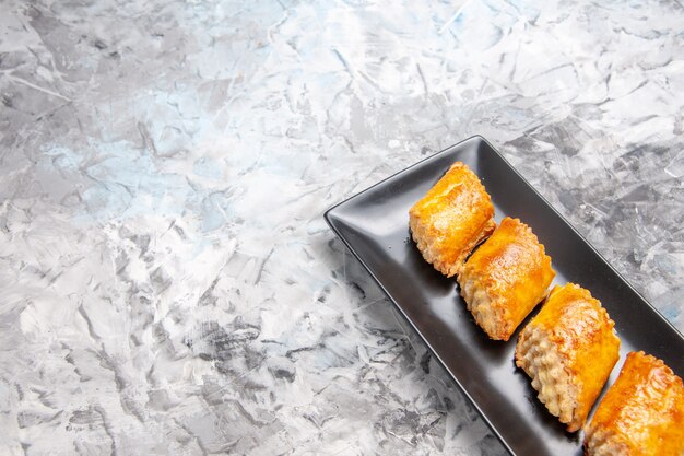 Vue de face de délicieuses pâtisseries sucrées à l'intérieur d'un moule à gâteau sur un gâteau sucré de pâtisserie à tarte de table blanche