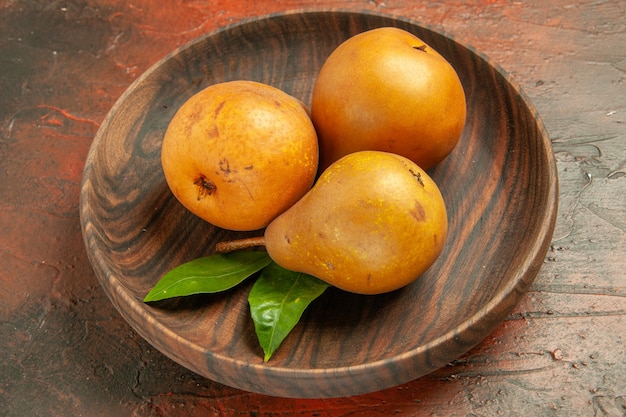 Vue de face de délicieuses poires sucrées à l'intérieur de la plaque sur fond sombre pulpe de fruit d'arbre photo de pomme