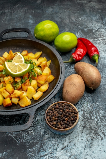 Photo gratuite vue de face de délicieuses pommes de terre frites au citron et aux poivrons sur une table grise